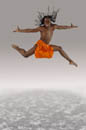 Leaping male dancer in orange loincloth costume and flying braids