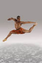 Leaping male dancer in orange loincloth costume