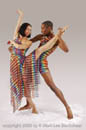 Two dancers in graceful pose and rainbow costumes